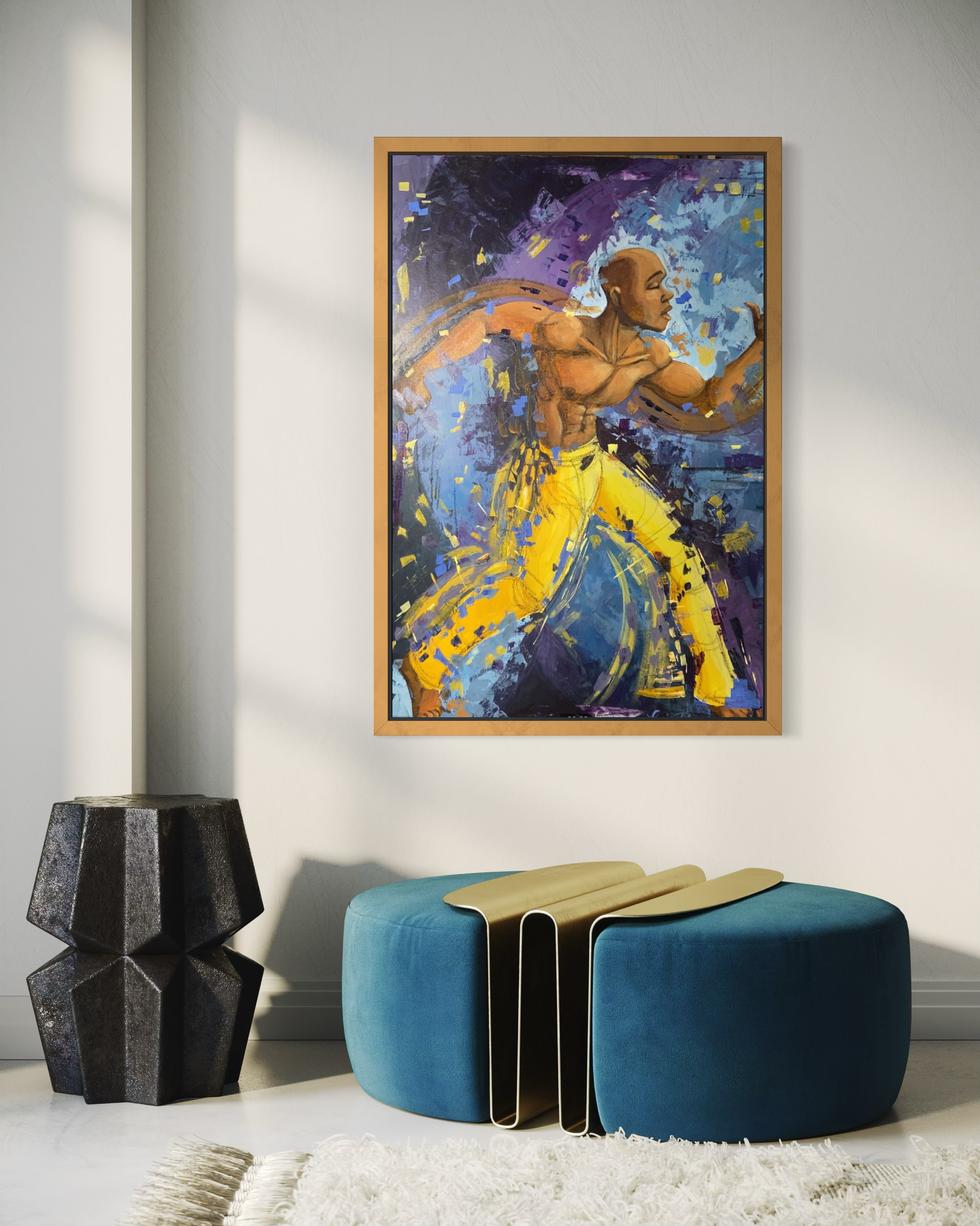 Framed abstract artwork of a muscular figure in a dynamic pose, placed above a blue ottoman in a room.